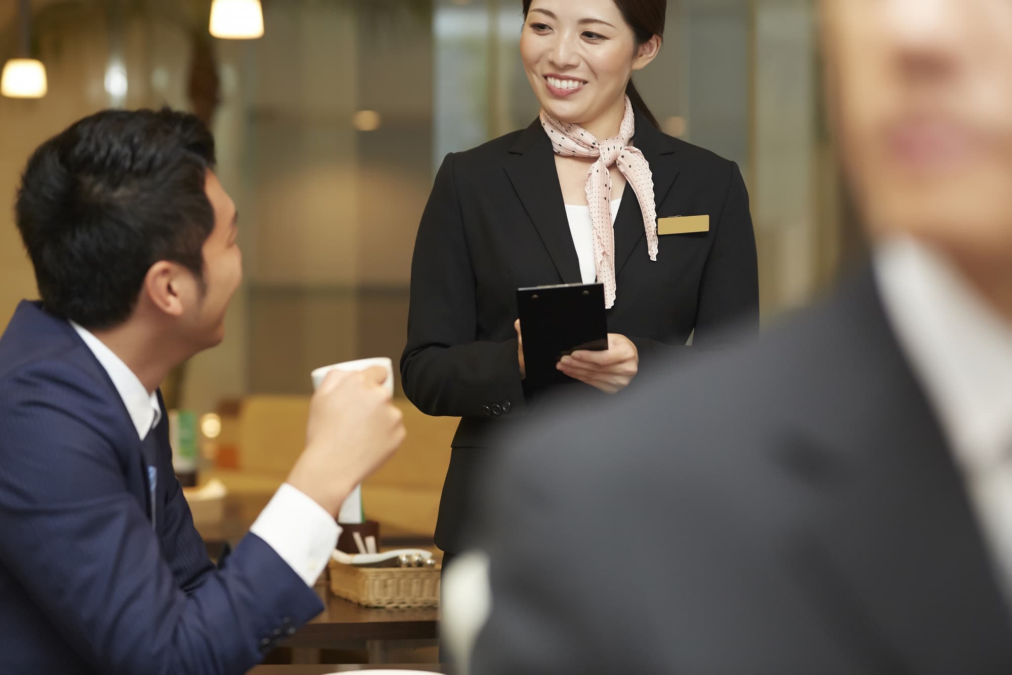 空港ラウンジサービススタッフ女性と男性客